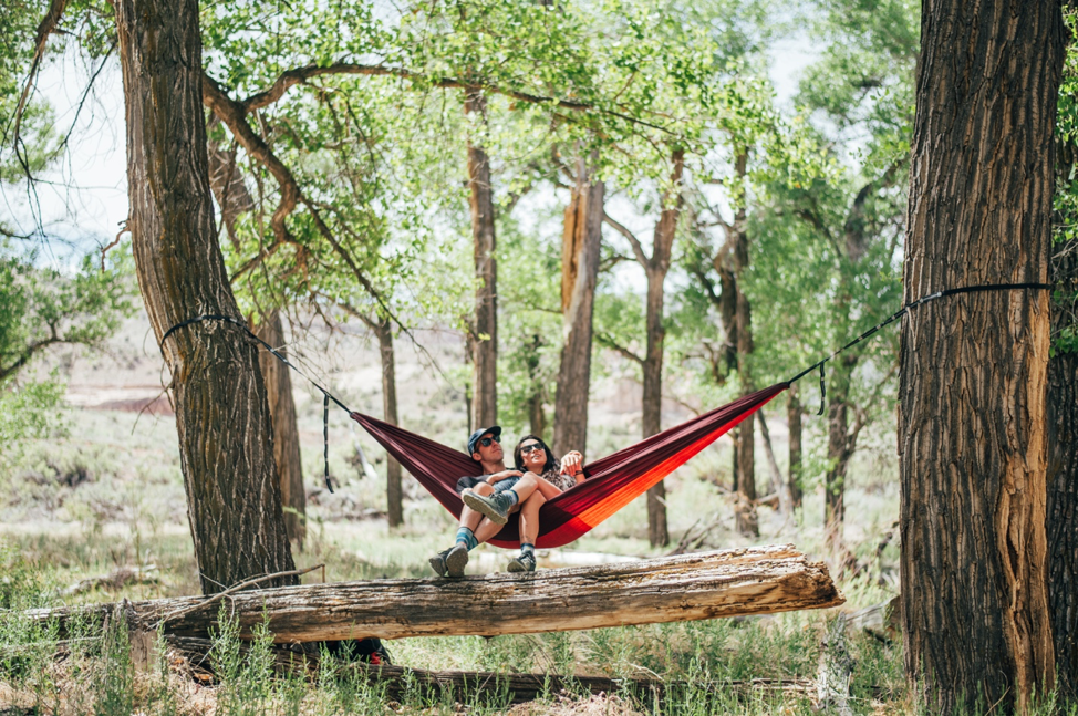 A picture of a couple sitting in a hammock in nature